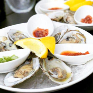 Oysters half shelled with lemon wedges and garnish on a plate of ice.