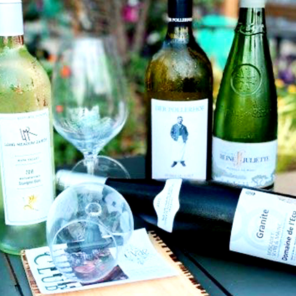 Wine bottles and glasses outside on a table.