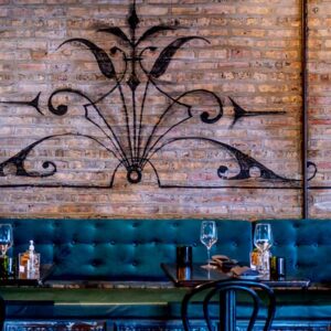 Teal bench along brick wall with set dingin tables.