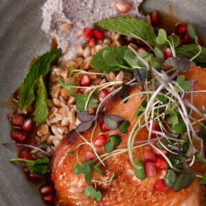 Chicken thigh with green garnish and pomegranate